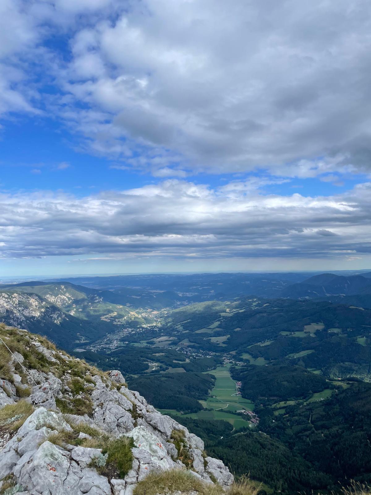 A wide view from a rocky mountain ridge over a green valley below